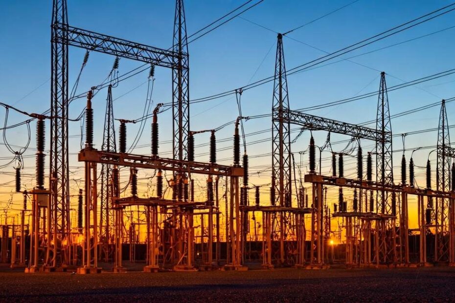 Sylwetka stacji elektroenergetycznej wysokiego napięcia z konstrukcjami kratowymi i liniami o zachodzie słońca