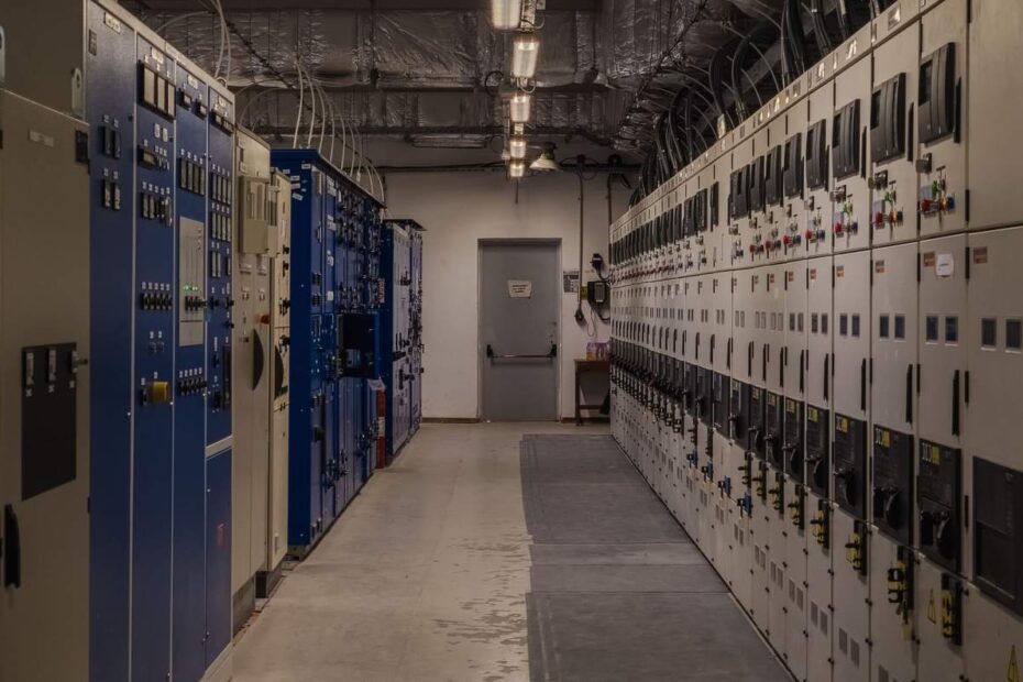 Wnętrze rozdzielnicy przemysłowej z rzędem szaf sterowniczych i pól rozdzielczych
