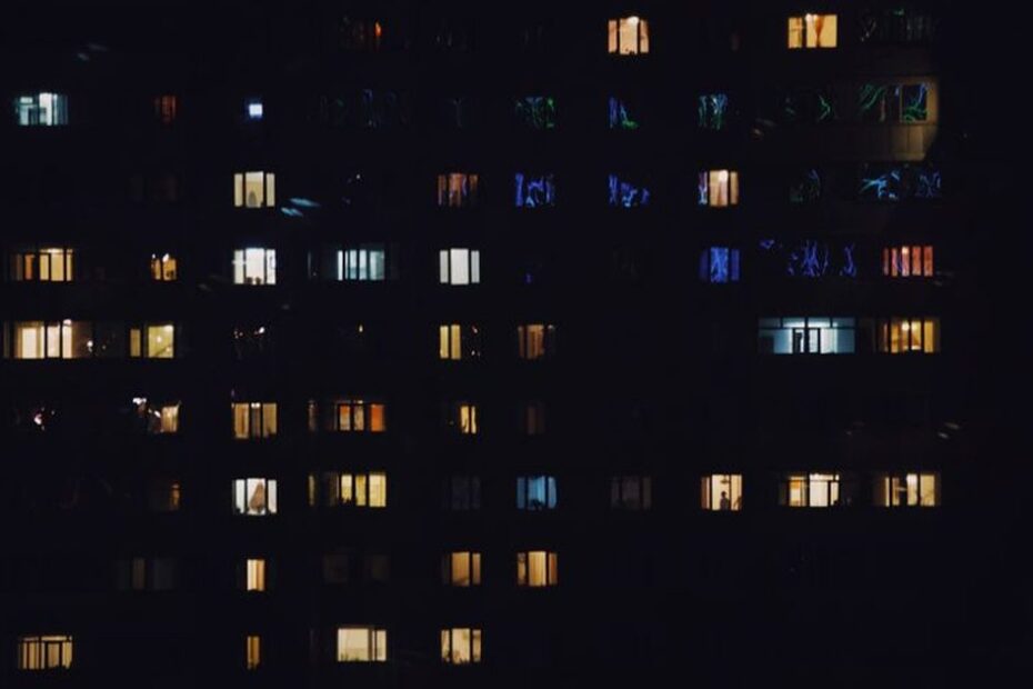 Blok mieszkalny nocą z rozświetlonymi oknami, obrazujący zużycie prądu w strefie nocnej